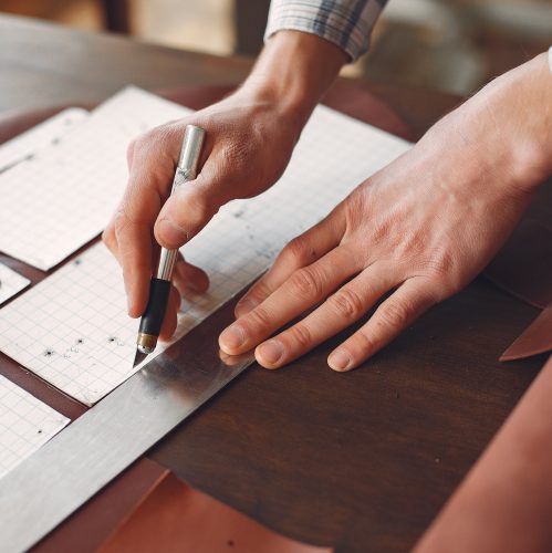 Man working with leather. Professional makes a wallet. erson measures the fabric.