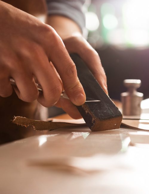 Close up of a shoemaker sharpening a knife at his workshop